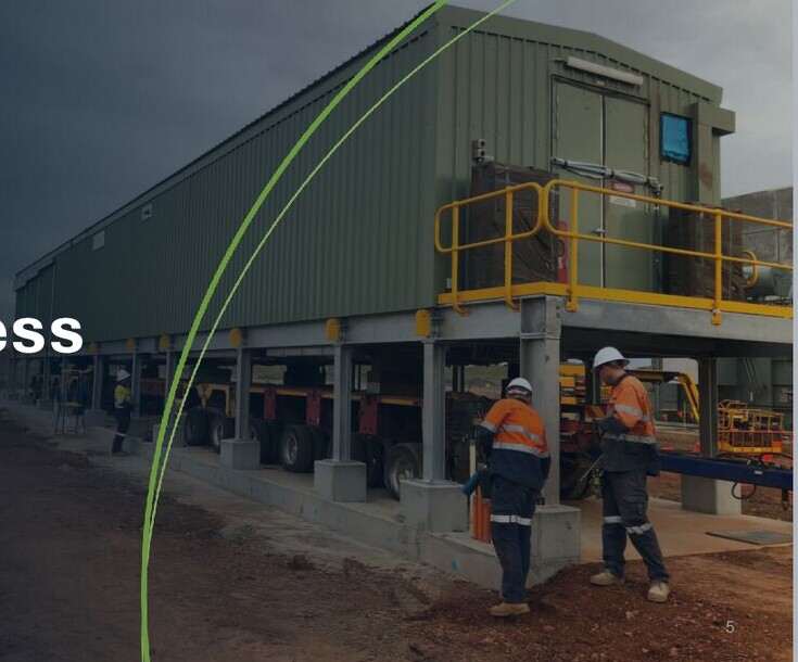 Transportable electrical switchroom on a multi-axle trailer, with two workers in high-visibility clothing beside it.