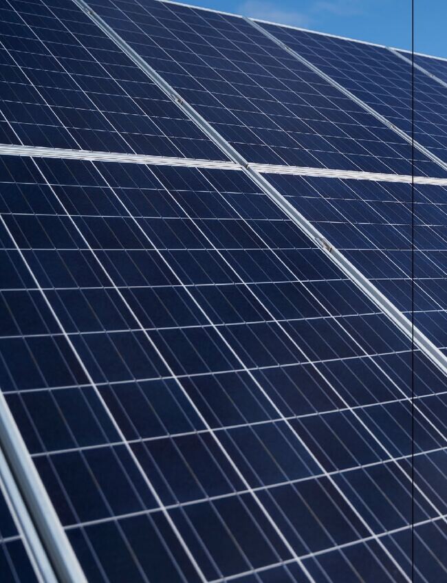 Close view of rows of blue photovoltaic solar panels under a clear sky.