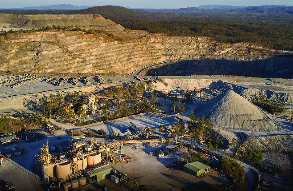 Aerial view of an open-pit mine, processing plant and surrounding bushland.