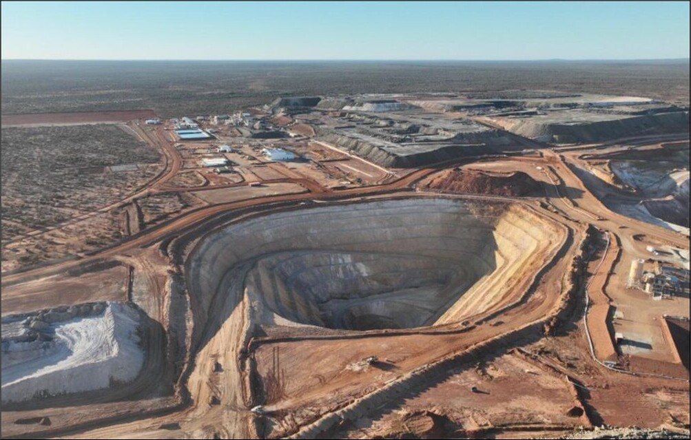 Aerial view of the Never Never open pit at the Dalgaranga gold mine, showing terraced pit walls, haul roads and surrounding mine infrastructure.