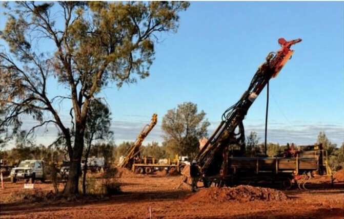 Diamond and RC drilling rigs operating at Metzke’s Find, with vehicles and dry woodland in the background.