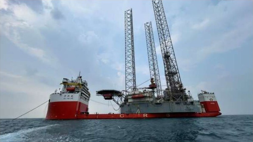 The Valaris 104 jack-up donor rig on a red transport vessel at sea, with its tall lattice legs raised above the deck.