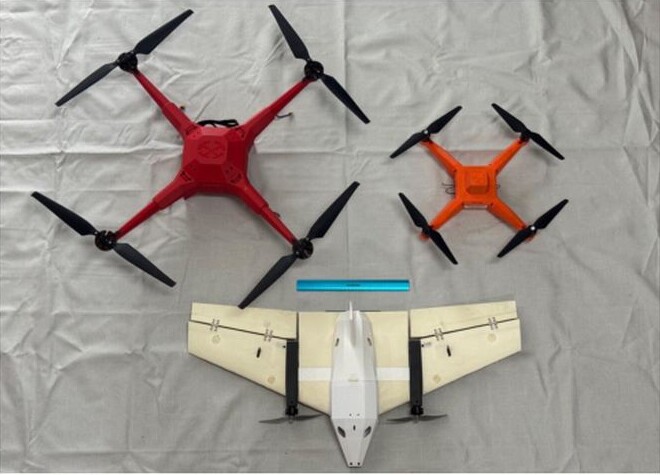 Three Boresight aerial target drones displayed on a grey surface: a red BQ-750, an orange BQ-400 and a white BF-100 fixed-wing drone with a blue ruler for scale.