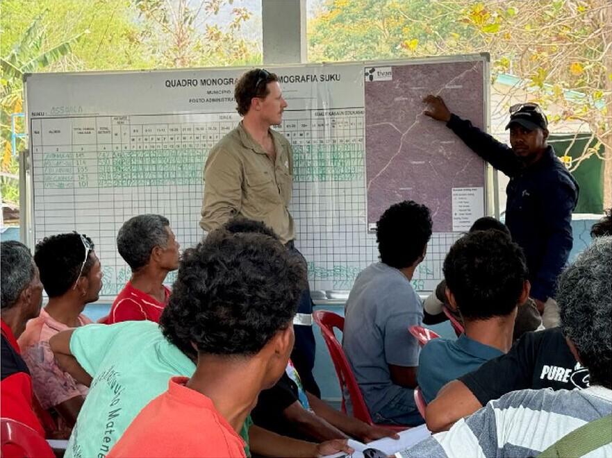 Tivan geologists host a local induction session in Ossoala, with attendees seated while a map is presented.