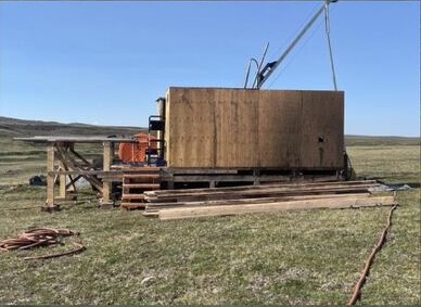Diamond drilling equipment and a small drill rig set up on open tundra at the Rae Project.
